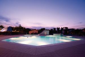 a large swimming pool at night with the lights on at Villaggio San Francesco in Duna Verde