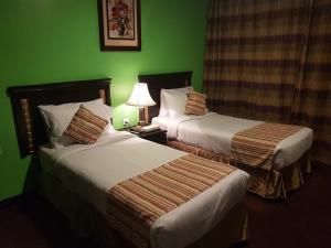 duas camas num quarto de hotel com paredes verdes em City Hotel no Cairo