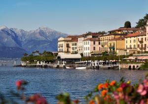 un groupe de bâtiments sur un lac avec des montagnes dans l'établissement Hotel Florence, à Bellagio