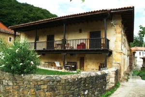 Casa antigua con balcón y pared de piedra. en Palacio Rural de Inguanzo de Cabrales, en Inguanzo