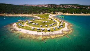 an island with tents and boats in the water at Arena Stupice Mobile Homes in Premantura