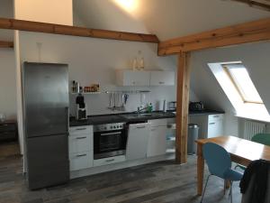 eine Küche mit einem Kühlschrank aus Edelstahl und einem Tisch in der Unterkunft Studio Templin in Templin