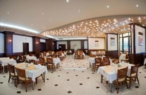 a restaurant with white tables and chairs and lights at ELPIDA Hotel - All Inclusive & Beach Front in Golden Sands