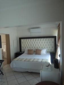 a bedroom with a large white bed with a large headboard at Bruno Comfort Suites in Johannesburg