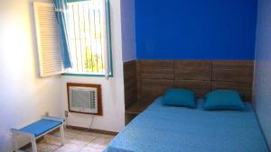 Dormitorio azul con cama y ventana en Pousada Recanto do Sossego, en Itamaracá