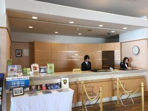 two people standing at a counter in a hotel lobby at Hotel Okhotsk Palace in Mombetsu