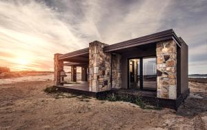 a stone house in the desert with the sunset in the background at Keros Blue - Luxury in Wilderness in Kalliópi