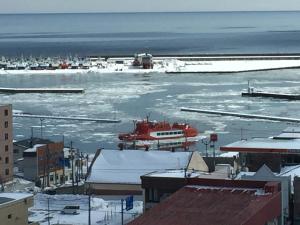 a red boat in a body of water with snow at Hotel Okhotsk Palace in Mombetsu