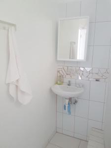 a white bathroom with a sink and a mirror at Evie Cottage in Bioche