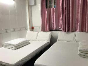 香港にあるビバリー ゲストハウスのピンクのカーテンが備わる小さな部屋のベッド2台