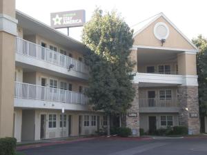 um grande edifício de apartamentos com uma árvore em frente em Extended Stay America Suites - Bakersfield - California Avenue em Bakersfield