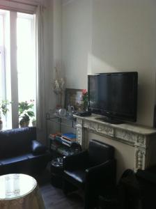 een woonkamer met een flatscreen-tv op een open haard bij Résidence18 in Brussel