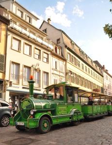 an old green trolley car on a city street at Appartement avec terrasse "BARTHOLDI" in Colmar
