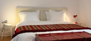 
a bed with two pillows and a night stand at Coimbra Vintage Lofts Apartments in Coimbra
