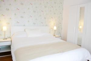 カディスにあるÁtico Compañíaの花柄の壁紙を用いた白いベッド付きのベッドルーム1室