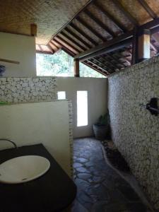 a bathroom with a sink and a stone wall at Jukung Bali Bungalow in Amed