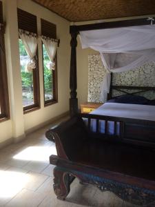 a bedroom with a bed in a room with windows at Jukung Bali Bungalow in Amed