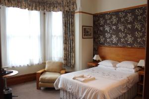 une chambre d'hôtel avec un lit et une chaise dans l'établissement Heatherbank Guest House, à Barnet