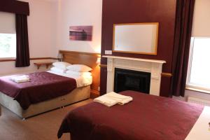 a hotel room with two beds and a fireplace at Heatherbank Guest House in Barnet