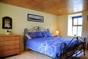 a bedroom with a blue bed and a wooden ceiling at Griffins Holiday Cottage in Dingle