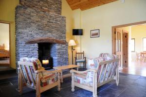 a living room with chairs and a stone fireplace at Griffins Holiday Cottage in Dingle