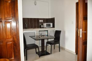 a small kitchen with a table and chairs and a microwave at Guest House Lumen in Lomé
