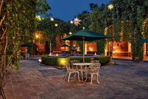 een patio met een tafel en stoelen en een parasol bij Hacienda Jurica by Brisas in Querétaro