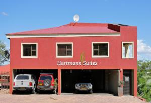 a red building with two cars parked in the garage at Hartmann Suites Serviced Self-Catering Apartments in Windhoek +6 photos