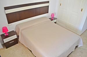a bedroom with a large white bed with pink lamps at Apartamento Benalmadena Costa in Benalmádena