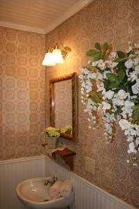 baño con lavabo, espejo y flores en Julian Gold Rush Hotel en Julian