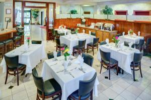 a restaurant with white tables and chairs with flowers on them at Lake Natoma Inn in Folsom