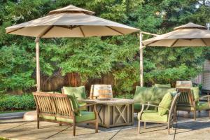 patio ze stołem, krzesłami i parasolem w obiekcie Lake Natoma Inn w mieście Folsom