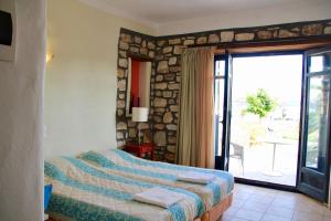 Schlafzimmer mit einem Bett und einer Glasschiebetür in der Unterkunft Porto Paradiso in Chrissi Akti