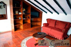 a living room with a red couch and a table at Casa La Carolina in Villa de Leyva