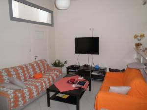 a living room with a couch and a tv at Rubini Rooms in Parikia