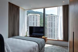 um quarto de hotel com uma cama e uma grande janela em Little Tai Hang em Hong Kong