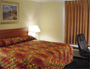 シェアアービルにあるHometown Inn & Suitesのベッド1台、椅子、窓が備わる客室です。