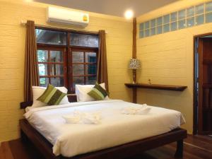 a bedroom with a large white bed with a window at Treasure Inn Khaoyai in Mu Si