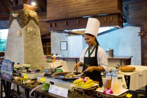 a woman in a chefs hat preparing food in a kitchen at Panviman Resort Koh Phangan - SHA Extra Plus in Thong Nai Pan Noi