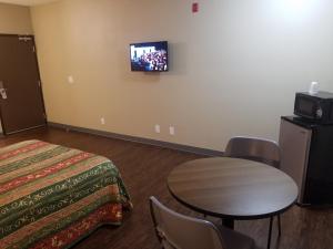 Habitación de hotel con mesa y TV en la pared en Travel Time Motel, en San Diego