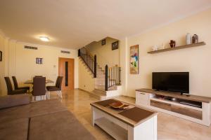 a living room with a couch and a television and a table at Residencial Playa de La Arena in Puerto de Santiago