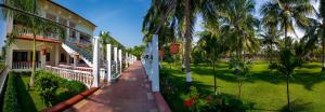 GReaT Trails Riverview Thanjavur By GRT Hotels في ثانجافور: مبنى فيه نخيل بجانب ساحة خضراء