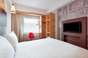 日惹ibis Yogyakarta Adi Sucipto的一间酒店客房,配有白色的床和电视