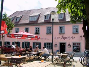a group of people sitting at tables in front of a pink building at Alte Apotheke in Radebeul