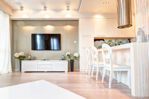 uma cozinha com armários brancos e uma mesa e cadeiras brancas em Apartment Royal em Białystok