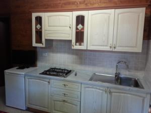 una cucina con armadi bianchi e lavandino di Camping Luni a Marina di Massa