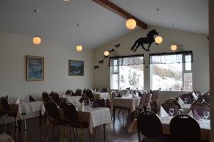 uma sala de jantar com mesas e cadeiras e um cavalo na parede em Dæli Guesthouse em Víðidalstunga