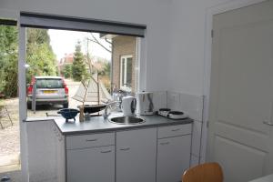 a white kitchen with a sink and a window at Zeeland aan Zee in Burgh Haamstede