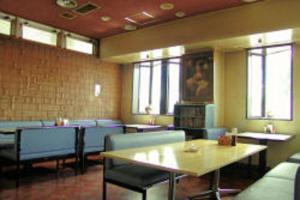 a dining room with tables and chairs and windows at Business Hotel Motonakano in Tomakomai