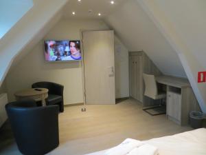 a attic room with a bed and a tv on the wall at B&B 't Hannonshof in Nieuwpoort